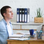 Man rubs back while sitting at desk