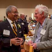 Awardee Olester Benson (left) converses with another person at the 2018 Alumni Awards ceremony.