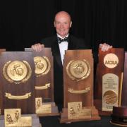 CU Skiing Coach Richard Rokos, standing with his NCAA Championship trophies