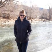 Elizabeth Koebele stands in her winter coat with the Arkansas River in the background.