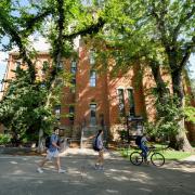 Campus community members walk past Old Main