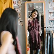 Person holding up a dress and looking in a mirror