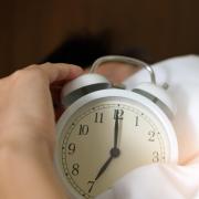 person in bed turns off an alarm clock