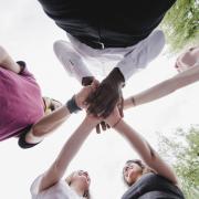 Young professionals stand in circle with hands together at center