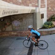 Person rides bike under bridge on CU campus