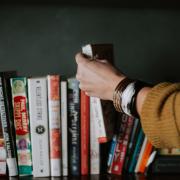 Woman pulls a book off a library shelf