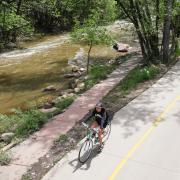 A student rides their bike along Boulder Creek