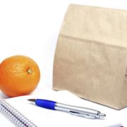 A brown bag, orange and notepad with pen