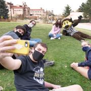 Students gather for a selfie with Chip the buffalo mascot outside 