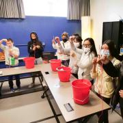 Young students dip their hands into buckets of frigid ice water