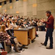 Carl Quintanilla speaks to students in large lecture hall