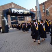 Graduates walk through Forever Buffs arch