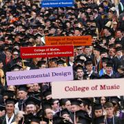 Graduation procession with signs designating each college 