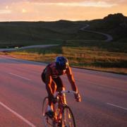 Cyclist on open road with sunset in the background