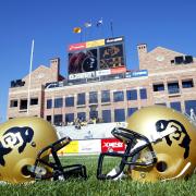 Two helmets are seen on the football field with the Dal Ward building in the background.