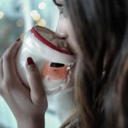 Person drinking hot chocolate out of a Santa mug