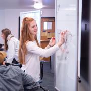 Student writes on a white board in the classroom