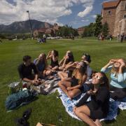 People sit on a campus lawn and take in the Great American Eclipse