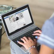 Woman checks Facebook on laptop computer