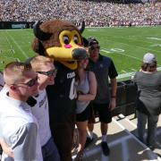 Family poses for photo with Chip at Family Weekend football game