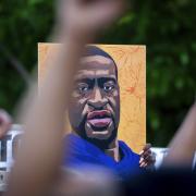 Protestors hold up painting of George Floyd 