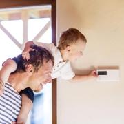 Father and young son adjust the thermostat in their home