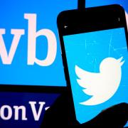 Person holding a phone with Twitter logo in front of a Silicon Valley Bank sign