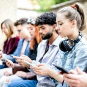 Young people sitting and scrolling on their phones