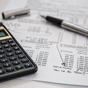 Financial statement with black calculator and silver pen