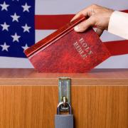 Person putting a Bible in a voting box