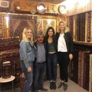 Three female college students pose with owner of carpet shop in Istanbul, Turkey