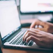 Hands typing on a laptop keyboard