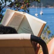 person reading a book by the lake