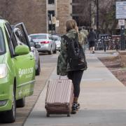 Student leaving campus with suitcase