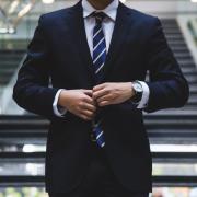 man in business suit adjusts his jacket and tie