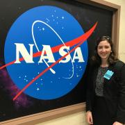 Maureen McNamara standing next to the NASA logo