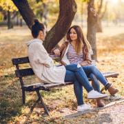 Two women talking on a bench.