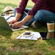 student sitting in grass working on a computer