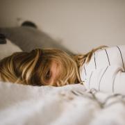 Girl lies face down on bed in clothes