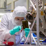 Technician in protective gear examines a computer chip