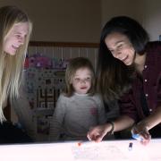 Researchers play with child over lighted table