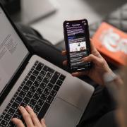 A person checks a laptop and mobile phone.