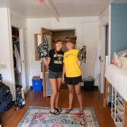 Two roommates pose for a photo in their dorm room