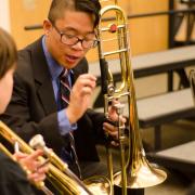 Middle School Ensemble participants with trombones reviewing music