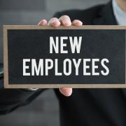 A hand holds a sign that reads "new employees"