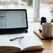 A laptop, cup of coffee and a notebook