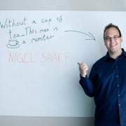 Nigel Sharp next to a whiteboard that reads "Without a cup of tea... This man is a monster"