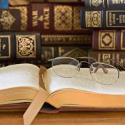 A stock image of old books with a pair of eyeglasses sitting on top of an open page.