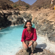 Alexis Templeton kneels on a rock in the middle of a spring