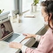 A person wearing a mask videoconferencing with someone